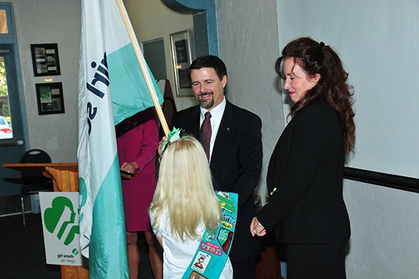 Rick Brooks accepts the Girl Scout flag from Girl Scout Junior Emersen Rider, daughter of Immediate Past Chair Debbie Rider (right).